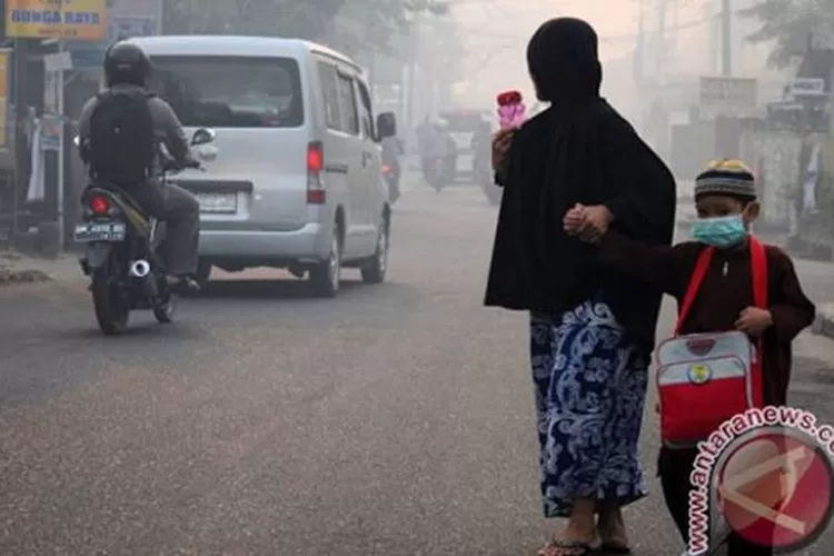 Seorang anak mengenakan masker medis ketika berangkat sekolah akibat asap pekat menyelimuti Kota Pekanbaru, Riau, beberapa waktu lalu.