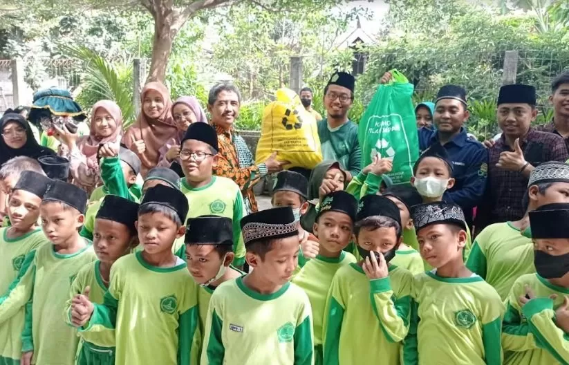 Rudi (kiri) menyerahkan kantong pilah sampah di MI Al Mahad An Nur Bantul. (Foto : Sukro Riyadi)