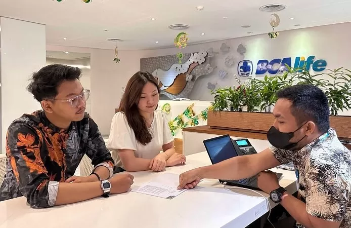 Customer service BCA Life sedang memberikan ilustrasi produk kepada nasabah. 