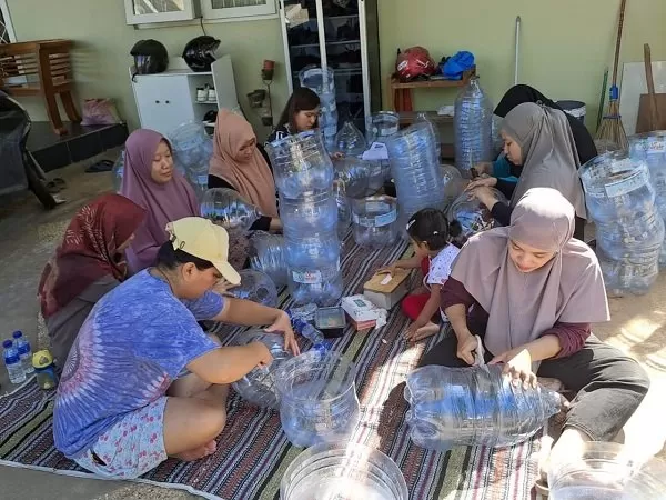 Ibu-ibu warga Cluster Jasmine Park Batursari Mranggen, bergotong-royong berkreasi merubah botol-botol bekas minuman kemasan untuk dirangkai menjadi gapura perumahan.