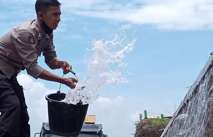 Anggota Sabhara Polres Bantul menyiramkan air untuk menghilangkan bau kurang sedap di lokasi kejadian kecelakaan.(Foto: Sukro R)