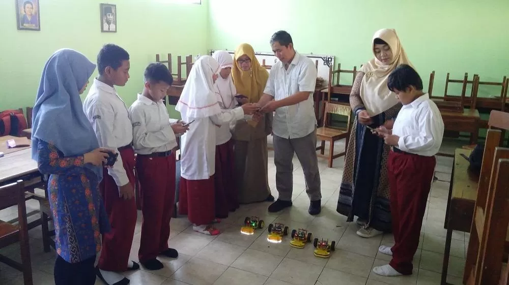 Siswa, guru dan dosen memandu siswa SD Muhammadiyah Pakel menggunakan robot. Foto: Jayadi Kastari