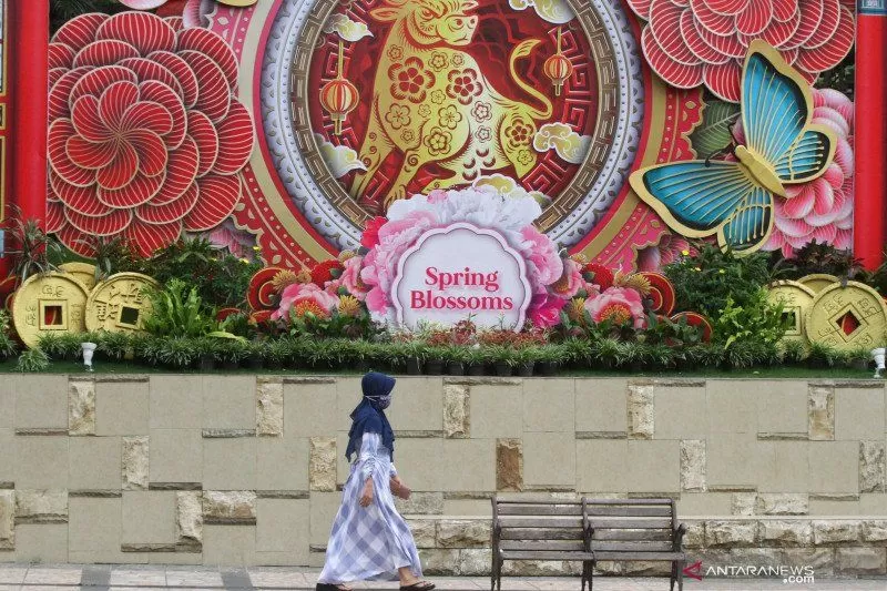 Pejalan kaki melintas di depan sebuah pusat perbelanjaan yang memajang dekorasi Imlek, di Malang, Jawa Timur, Senin (8/2/2021). Dekorasi Imlek dengan tema shio kerbau logam tersebut sengaja dipasang untuk menarik minat masyarakat agar datang berkunjung