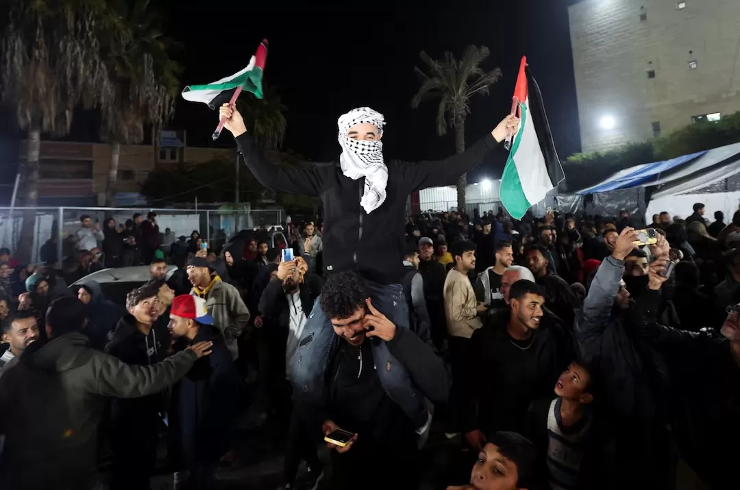 Seorang pria melambaikan bendera Palestina saat warga Palestina bereaksi terhadap berita tentang kesepakatan gencatan senjata dengan Israel, di Deir Al-Balah di Jalur Gaza tengah. (Foto: reuters.com)