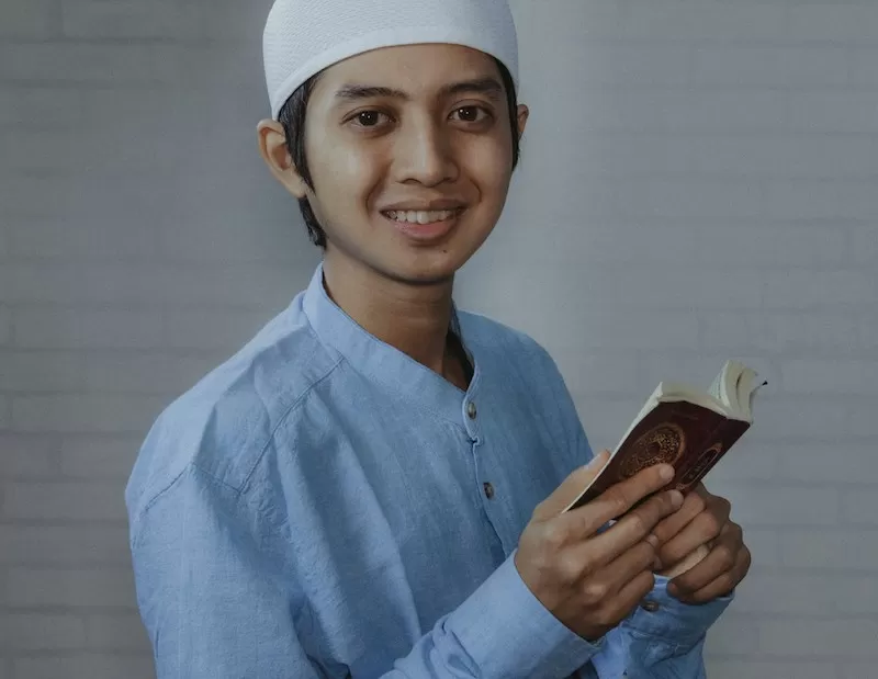 Ilustrasi Pria Asia memegang Quran. Foto: Unsplash/Afif Ramdhasuma  