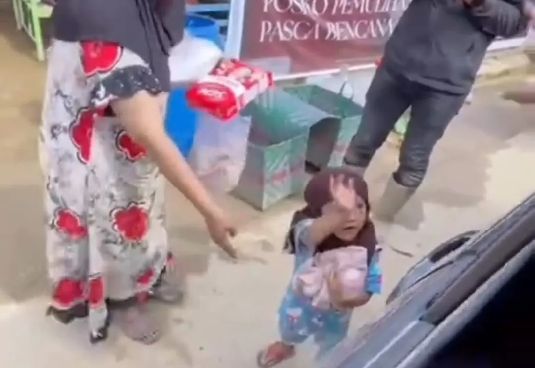 Tangkapan layar seorang bocah yang dengan gembira menerima bantuan makanan dan pakaian di tengah suasana pengungsian banjir Aceh Tamiang. (TikTok/zaits_bf)