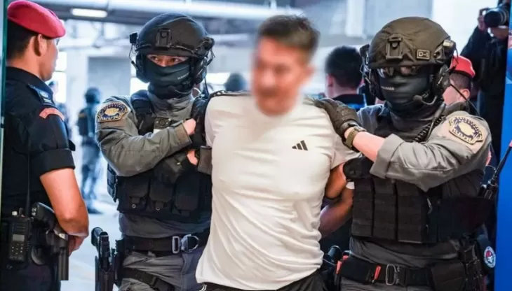 Dua polisi mengapit bos judol She Zhijiang saat akan Thailand ekstradisi ke China. (Foto: Kepolisian Thailand)