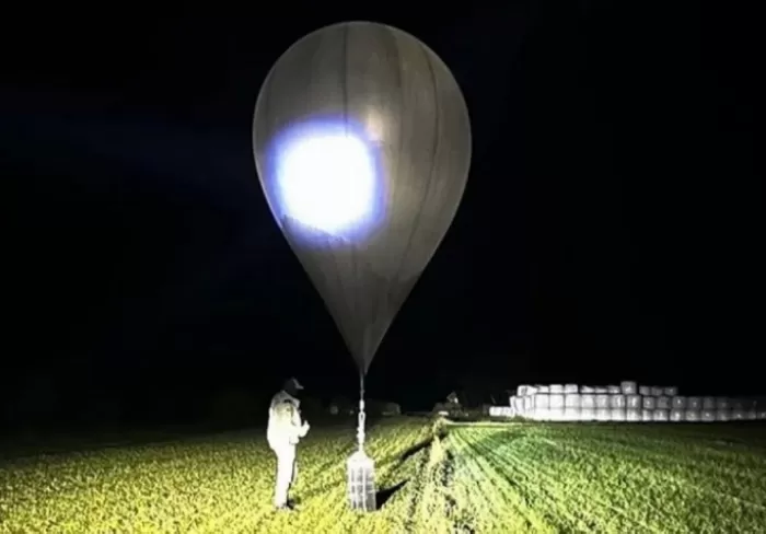 Dalam foto yang tidak bertanggal yang dirilis oleh Dinas Penjaga Perbatasan Negara Lithuania, seorang petugas memeriksa balon yang digunakan untuk membawa rokok ke Lithuania. (Istimewa)