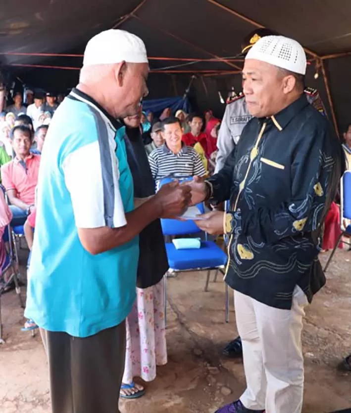 SERAHKAN BANTUAN: Bupati Tanbu H Sudian Noor (kanan) menyerahkan bantuan untuk korban kebakaran di Desa Sungai Bali Kabupaten Kotabaru yang diterima kepala desanya Ujang Arhadi. (Foto Diskominfo Tanbu For Radar Banjarmasin).