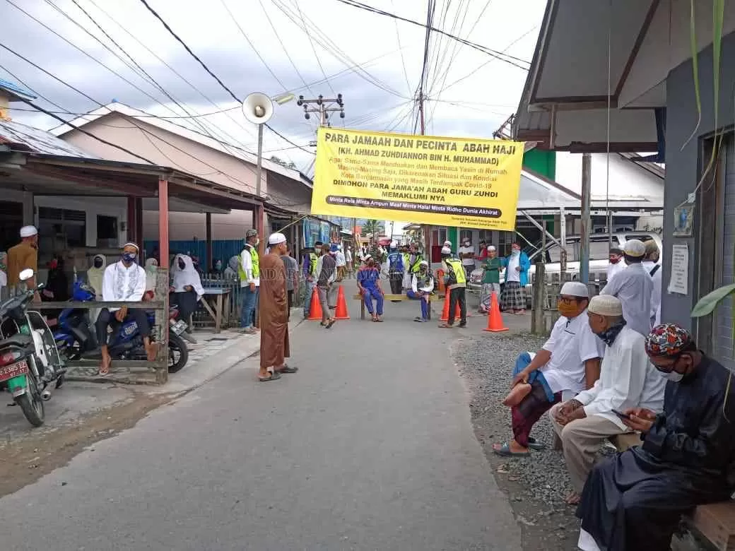 MENUNGGU: Pelayat masih menunggu kedatangan almarhum Guru Zuhdi di pintu masuk jalan menuju kediaman beliau.|Foto: M Oscar Fraby/Radar Banjarmasin