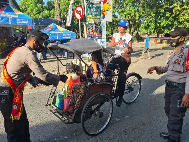 BAGI MASKER: Anggota Polresta Banjarmasin membagikan masker kepada warga yang melintas di jalan sembari mensosialisasikan Perwali Nomor 68.