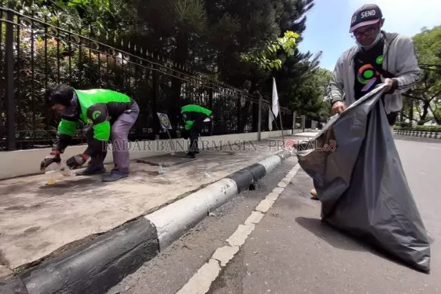 KEREN: Para penarik ojek online yang kerap mangkal di sekitar gedung DPRD, Jalan Lambung Mangkurat, memunguti  sampah sisa unjuk rasa, kemarin. | FOTO: WAHYU RAMADHAN/RADAR BANJARMASIN