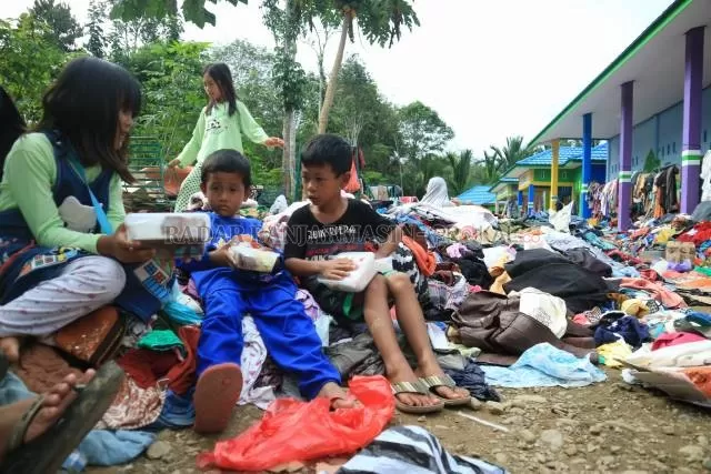 DAMPAK: Anak-anak korban bencana banjir di Desa Hantakan, HST, duduk di atas tumpukan pakaian bantuan. | FOTO: RASIDI FADLI/RADAR BANJARMASIN