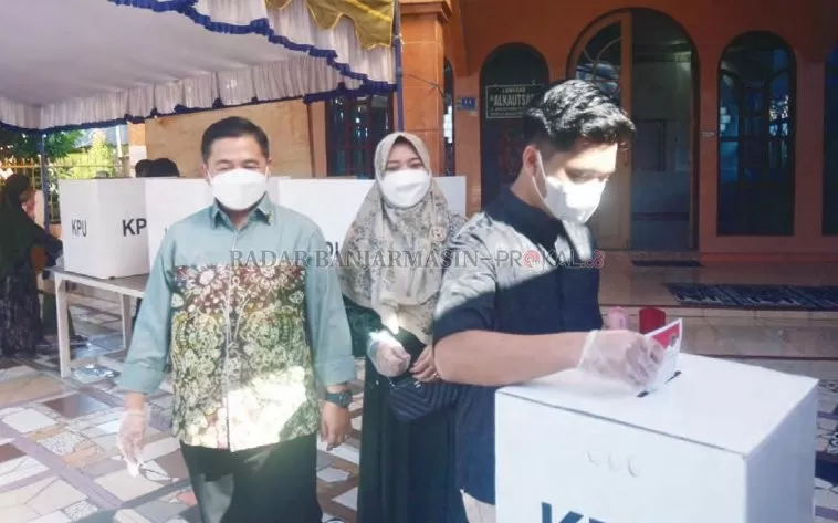 BARENG KELUARGA: Putra sulung Ibnu Sina memberikan hak suara dengan disaksikan orang tuanya di TPS 02 Pemurus, kemarin (9/6).