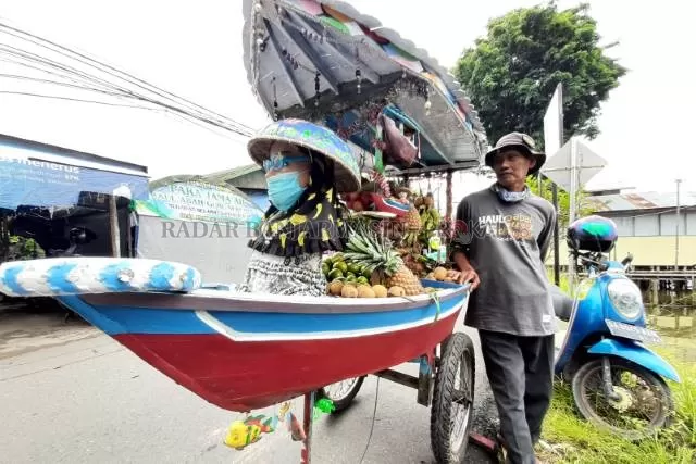 JUKUNG DORONG: Fahrul, 55 tahun, berpose di samping jukung darat kebanggaannya. Selama 20 tahun ia berdagang di Pasar Terapung. | FOTO: WAHYU RAMADHAN/RADAR BANJARMASIN