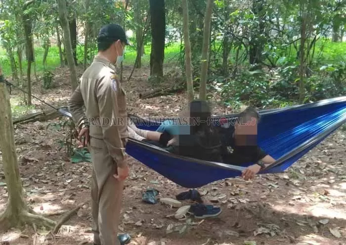 ASYIK BERMESRAAN: Petugas Satpol PP memergoki sejoli yang berbuat tak pantas di dalam ayunan gantung atau hammock di Hutan Pinus Banjarbaru. Foto: Satpol PP Banjarbaru for Radar Banjarmasin