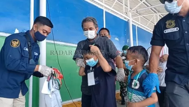 TIBA DI TANAH AIR: Kepala Disnakertrans Nunukan, Abdul Munir mendampingi Moch. Khairil Bin Aris (8) dan Moch. Hasril Bin Aris (6) saat tiba di Pelabuhan Tunon Takan, Nunukan, Kamis (21/10). FOTO: ASRULLAH/RADAR TARAKAN