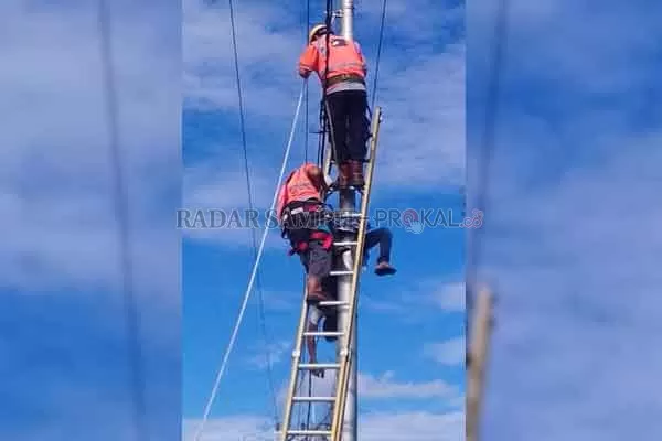 EVAKUASI: Petugas PLN berusaha menurunkan jenazah Sigit Sutrisno yang tewas karena tersengat listrik, Minggu (11/4). Tubuhnya sempat tergantung sekitar satu jam.( DODI/RADAR SAMPIT)