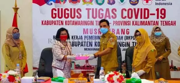 SERAHKAN: Bupati Kotim Supian Hadi, saat menyerahkan kue dalam rangka peringatan Hari Kartini yang ke- 104 tahun kepada Ketua DPRD Kotim Rinie A Gagah, di tengah pandemi Covid-19, tahun ini peringatan Hari Kartini tanpa ada perayaan, Selasa (21/4).(YUNI/RADAR SAMPIT)