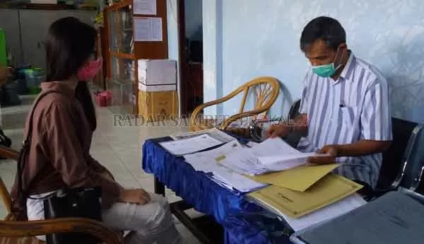 JAGA JARAK: Kepala SMAN 2 Sampit Kodarahim melayani siswinya yang mengambil surat keterangan lulus (SKL).(TONO/RADAR SAMPIT)