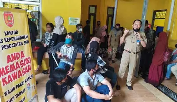 TURUN TANGAN: Kepala Disdukcapil Kotawaringin Barat Gusti Imansyah menyampaikan kepada masyarakat yang mengurus adminduk untuk tetap jaga jarak dan menggunakan masker di ruang pengambilan berkas disdukcapil, Senin (22/6).(RINDUWAN /RADAR PANGKALAN BUN )