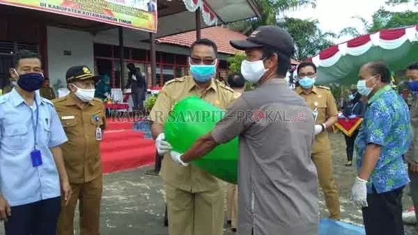 BANTUAN: Kepala Dinas Perikanan Heriyanto, menyerahkan bantuan benih ikan kepada kelompok pembudidaya perikanan (Pokdakan) di halaman kantor Kecamatan Mentaya Hulu, Senin (22/6).(IST/RADARSAMPIT)