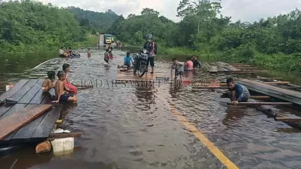 BANJIR : Salah seorang pengendara motor memanfaatkan penyeberangan rakit saat melintasi genangan banjir di jalan trans kalimantan.(RIA MEKAR/RADAR PANGKALAN BUN)