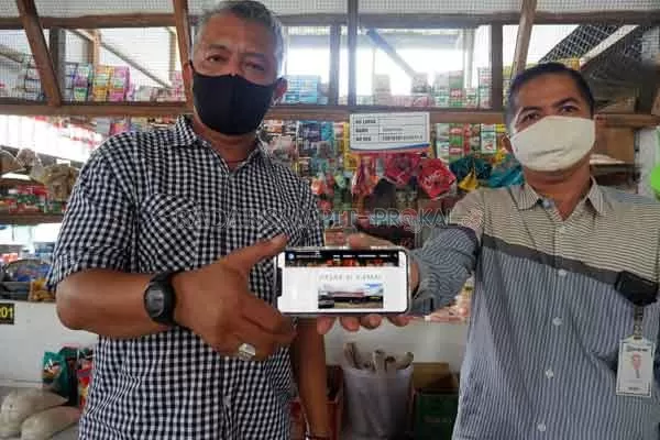 PASAR UNGGULAN:  Pengelola Pasar Alkamal Supriyadi Elyas bersama Asisten Manager BRI Cabang Sampit Komarudin, memperlihatkan layanan web pasar. Lewat layanan ini pembeli bisa belanja tanpa harus datang langsung ke Pasar Alkamal.(USAY NOR RAHMAD/RADAR SAMPIT)