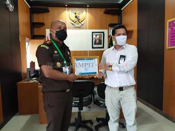 PENGHARGAAN : Kepala Kejaksaan Negeri Kobar, Dandeni Herdiana menerima penghargaan dari PT.PLN atas peran serta tim Jaksa Pengacara Negara dalam pembebasan dan pembangunan Jaringan Transmisi SUTT di Kobar.(SYAMSUDIN/RADAR PANGKALAN BUN)