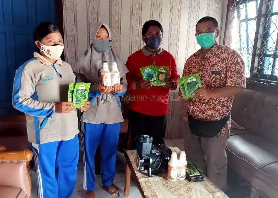 PEMBERDAYAAN PKK : Community Development Officer (CDO) PT. GSDI, Tria Ksatriamansyah (kanan) saat menyerahkan bantuan benih dan sejumlah peralatan pendukung lainnya. Traktor bajak sedang mengerjakan pengolahan lahan untuk tanaman sayuran PKK. (ISTIMEWA/RADAR PANGKALAN BUN)