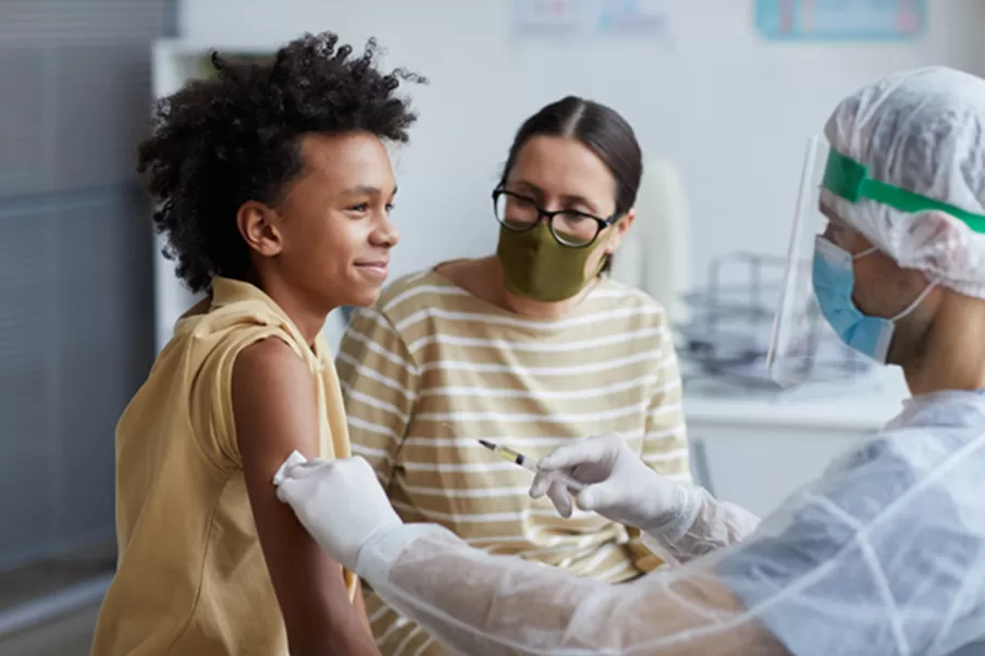 Side view portrait of teenage African-American boy smiling happily during covid vaccination in clinic, copy space