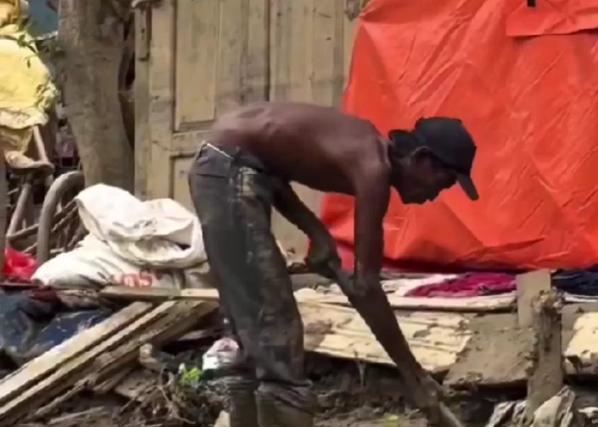 Potret seorang warga sedang membersihkan lumpur di depan bangunan yang rusak.  (X/Aceh)