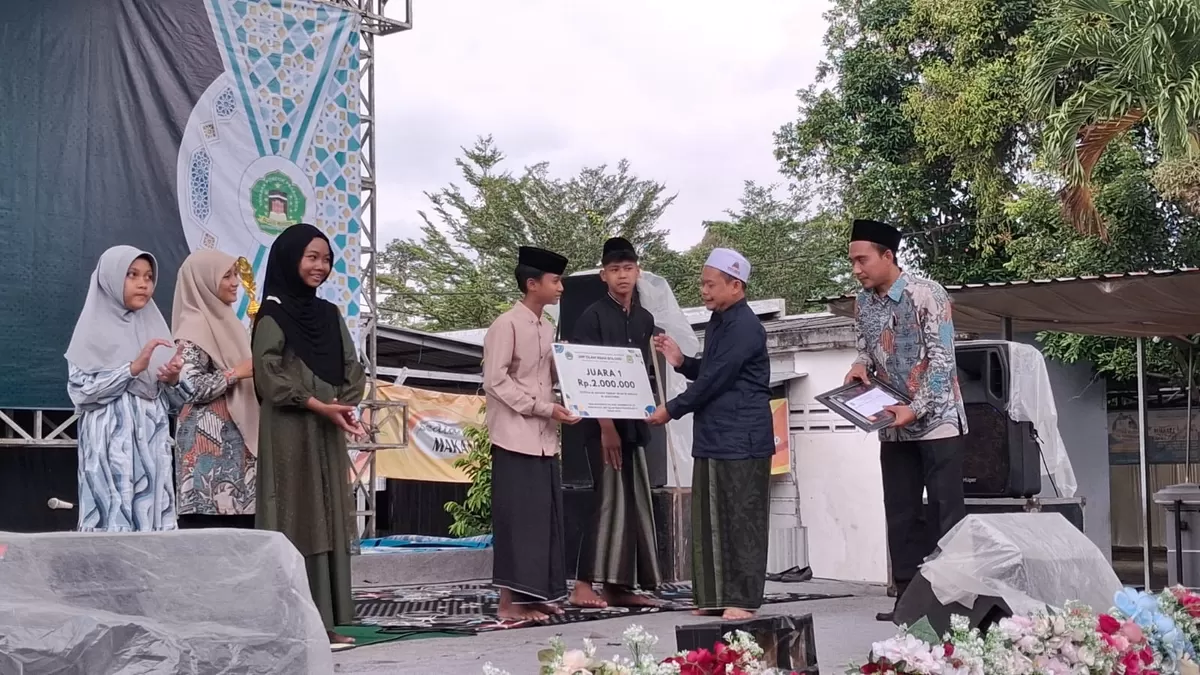 Pengasuh Ponpes Falahul Muhibbin KH Nur Hadi menyerahkan hadiah kepada juara pertama. (SketsaNusantara.id)
