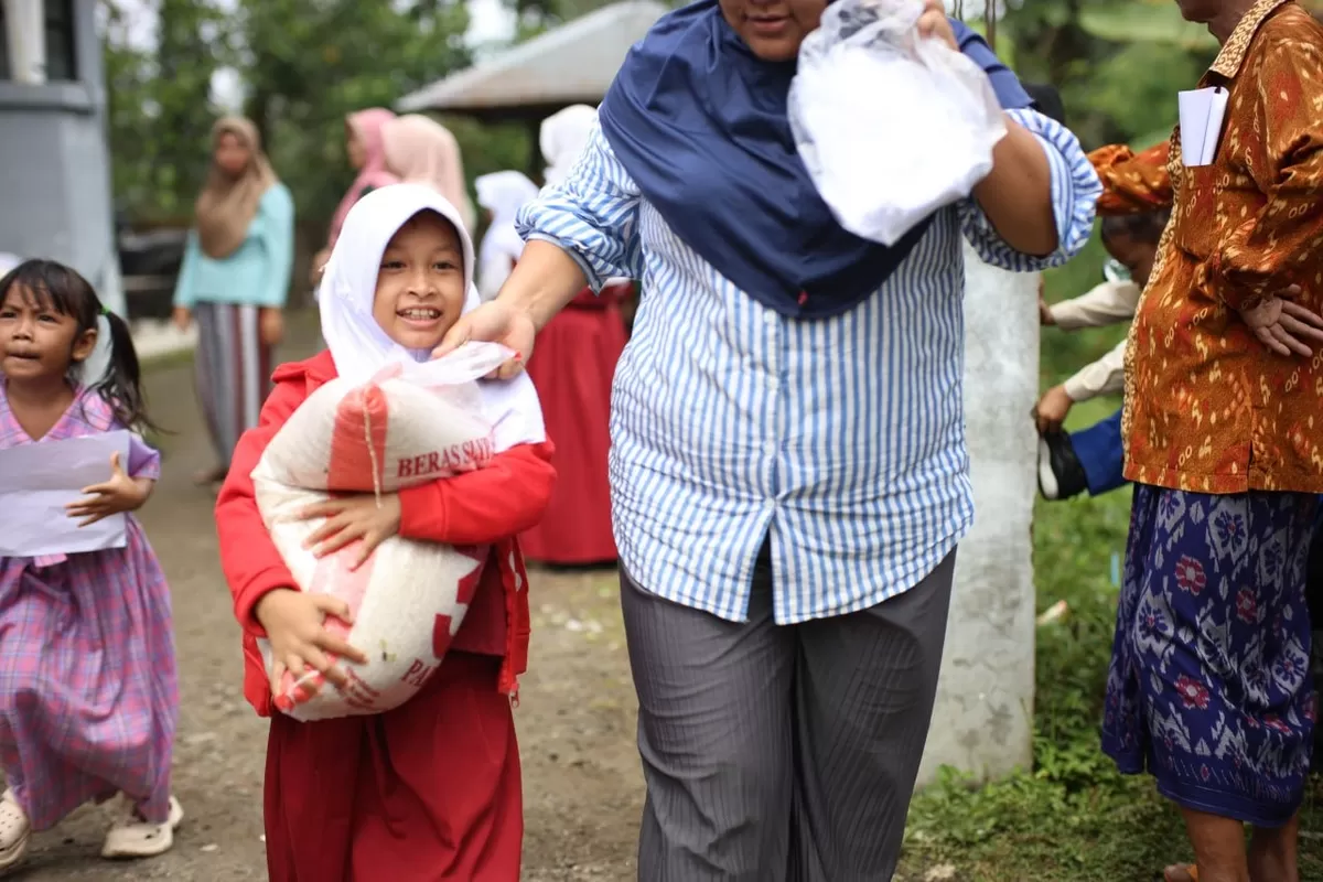 Seorang anak sekolah tampak gembira didampingi walintya setelah menerima paket pangan yang telah disiapkan. (Ist)