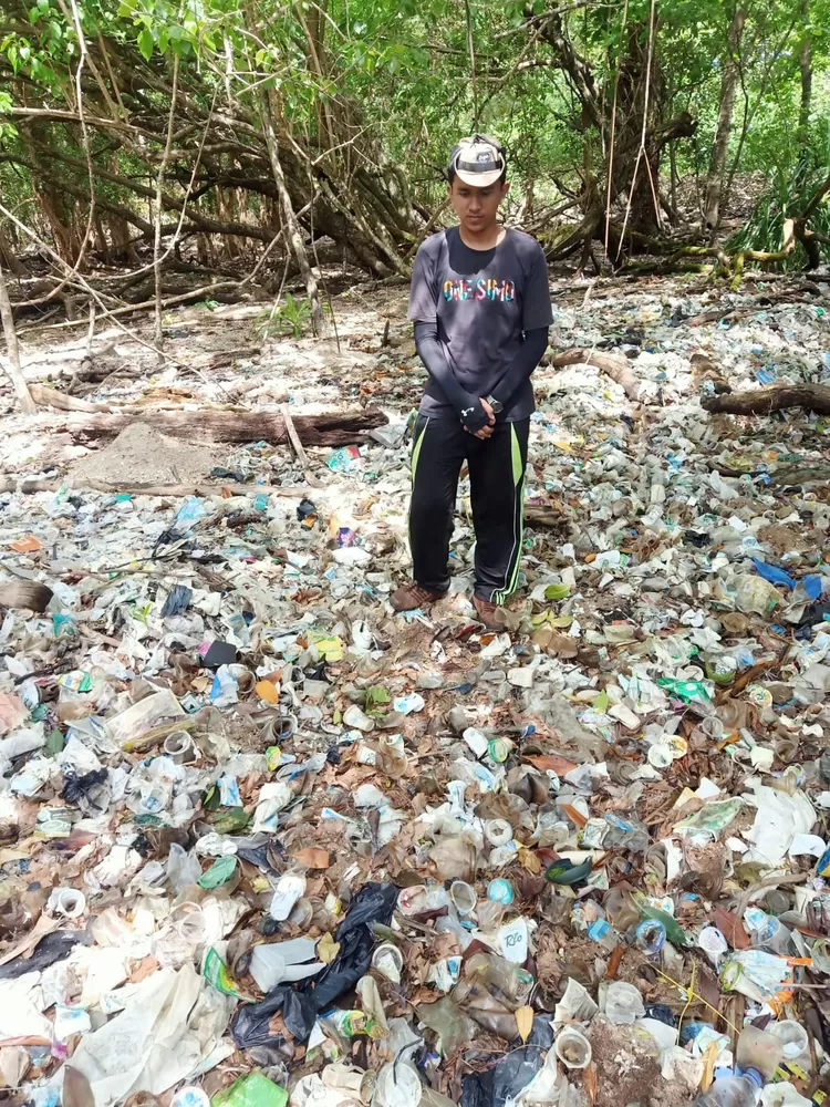 Ilustrasi foto, Petani Madu berdiri di hamparan sampah di Pantai Ujung Kulon