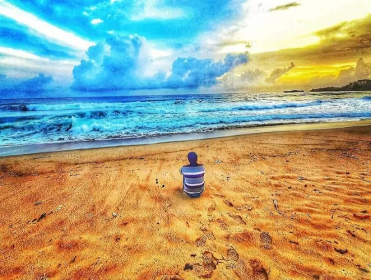 Pose foto duduk sendirian menatap laut lepas difoto dari belakang