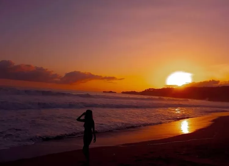 Pose foto jalan di tepian pantai kala sunset