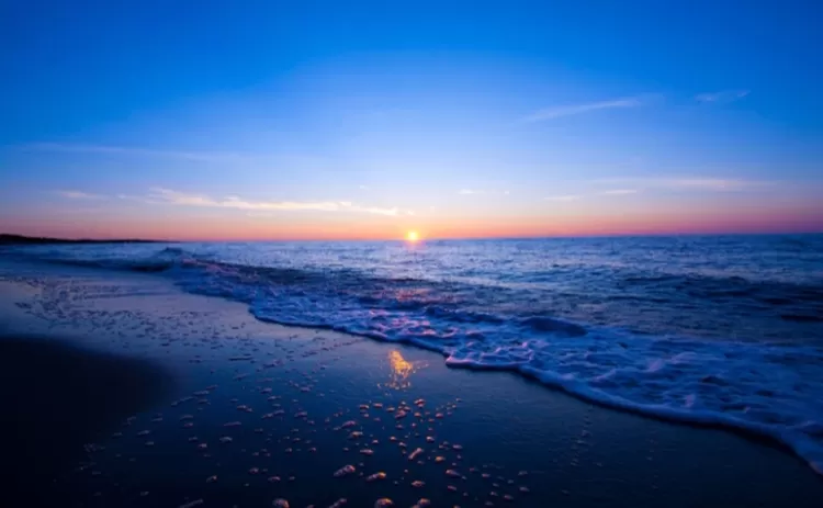 Inspirasi foto sunset di Pantai Pidakan sunset dengan buih ombak tipis di pantai yang tenang