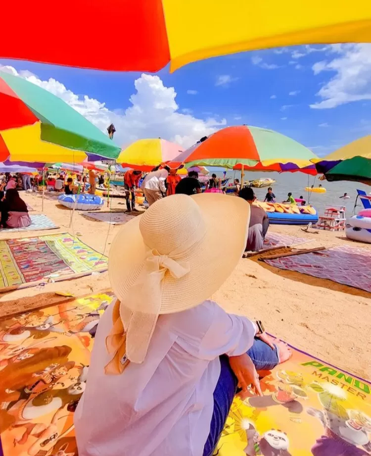 Spot foto keren di destinasi wisata alam Pantai Takisung Banjarmasin salah satunya adalah dibawah payung tepian laut.