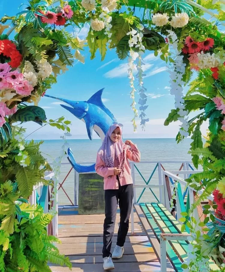 Spot foto keren di destinasi wisata alam Pantai Takisung Banjarmasin salah satunya adalah di dekorasi bunga dan ikan lumba-lumba.