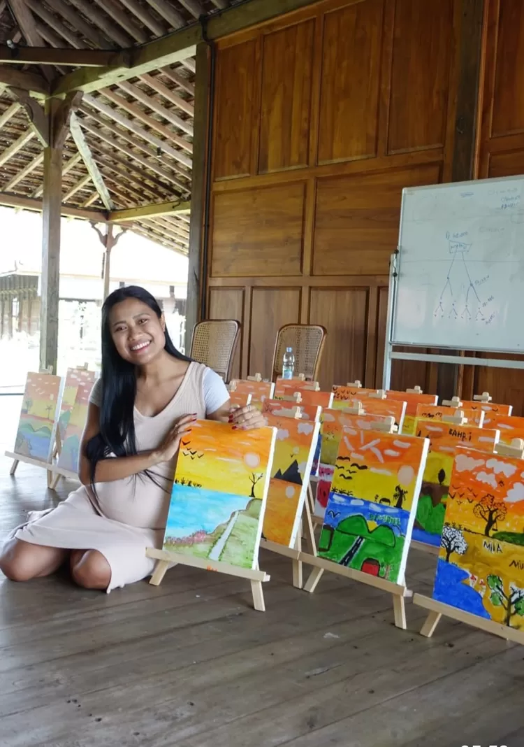 Migi menunjukkan hasil karya lukisan  anak- anak  yg belajar dengannya di Rumah Joglo , Tanjung Lesung,   Banten , Minggu (19/6/2023).
