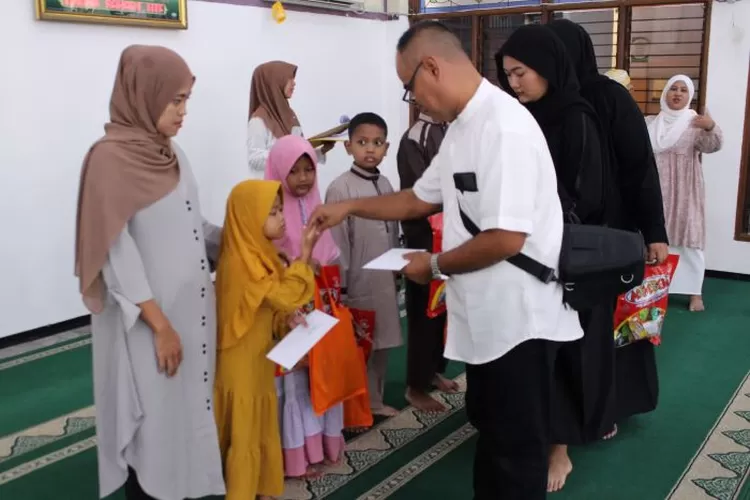 Bendahara Umum DKM Baiturrahim, Luki Mandara, memberikan santunan kepada anak yatim.