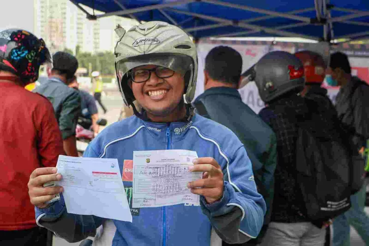 Seorang warga pengendara sepeda motor  memperlihatkan  surat  keterangan hasil uji  emisi kendaraannya.