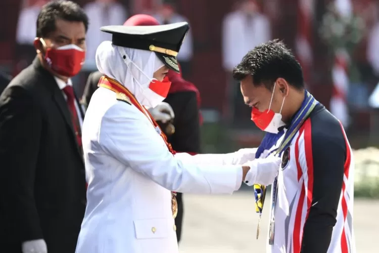Gubernur Jatim Khofifah Indar Parawansa menyematkan tanda kehormatan Lencana Jer Basuki Mawa Beya Emas kepada lifter Eko Yuli Irawan usai upacara pengibaran bendera memperingati HUT Ke-76 RI di Gedung Negara Grahadi di Surabaya, Selasa (17/8/2021).  (ANTARA/HO-Biro Adpim Jatim)