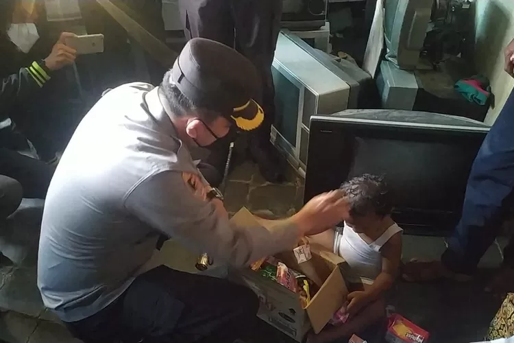 Kapolres Tegal AKBP Rahmad Hidayat mengusap kepala Nando saat memberikan bantuan sembako, makanan dan uang, Senin pagi(13/9/21) (K.Wijayanto)