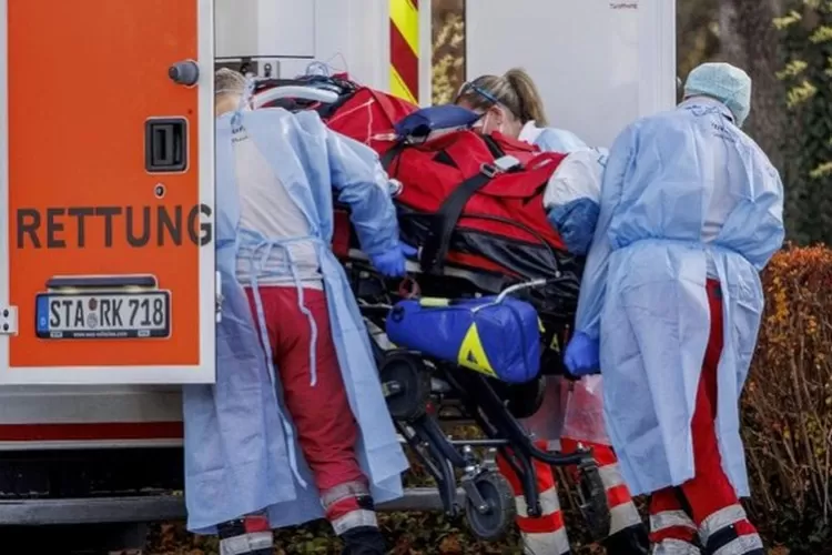 Petugas penyelamat membawa pasien perawatan intensif Covid 19 dari helikopter penyelamat udara ke kendaraan ambulans di lapangan olahraga di Herrsching, Jerman, Jumat, 19 November 2021. (Foto: Balk/dpa via AP)
