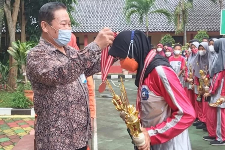 Kepala SMPN 3 Batang, Bambang Purwantyono, mengalungkan medali kepada salah satu siswa yang meraih prestasi di Popda 2021, Sabtu 4 Desember 2021.  (dok)