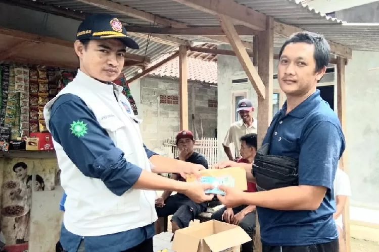 Ketua Kartar Desa Cogreg, Ikhsan Saipul Munir serahkan bantuan hasil penggalangan dana pada perwakilan panitia, Ketua RT Ferry. (Rosyka/Bogor Times)