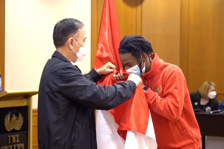 Striker muda timnas Indonesia, Ronaldo Kwateh mencium bendera merah putih di hadapan Ketum PSSI Mochamad Iriawan. WADA resmi cabut sanksi larangan pengibaran bendera Indonesia. (dok PSSI)
