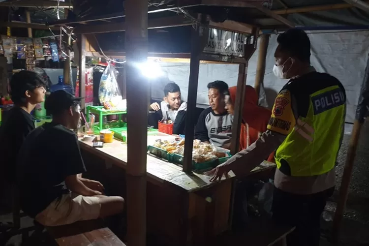 Petugas Polsek Weleri memberikan teguran kepada warga yang masih berkerumun di sebuah angkringan hingga larut malam.  (edi prayitno/kontributor Kendal)